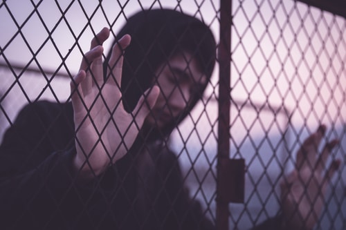 Asian man leaning on cage