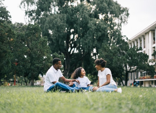 Family Sitting On A Lawn In Front Of House