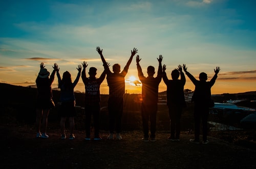 Group Of People With Arms Raised Facing Horizon