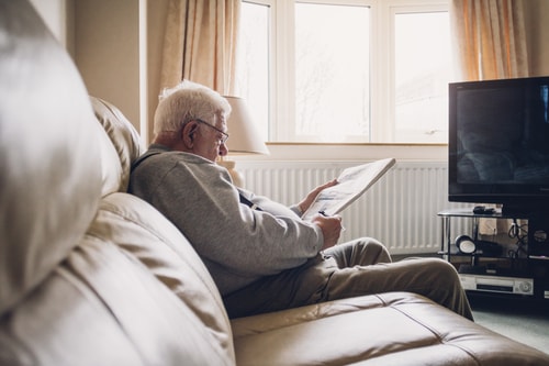 Man sitting on sofa reading paper
