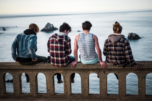 Four young people sitting on bridge