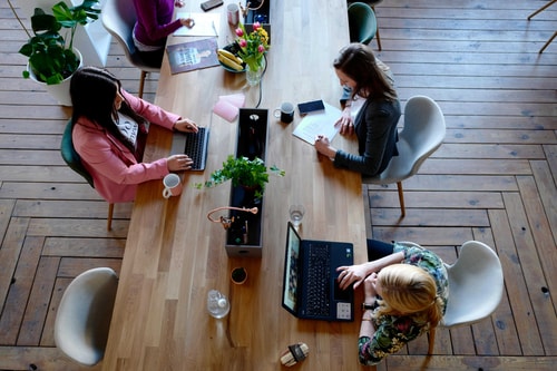 Three-woman-sitting-on-white-chair-in-front-of-table