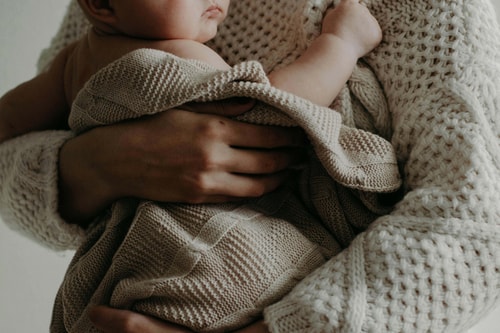 A lady holding a baby in a blanket