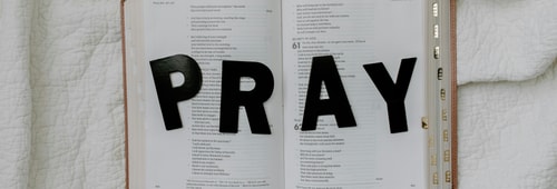 The word pray on an open bible