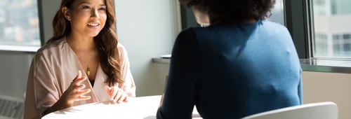 Two women talking over table