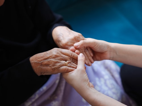 Young woman holding elderly hands